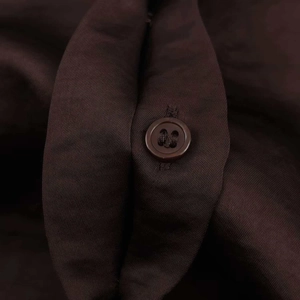 Macro detail of silky satin texture and brown button on dark coffee autumn shirt