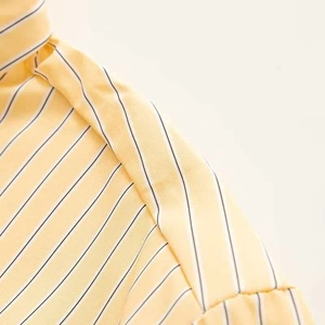 Detailed view of yellow striped shirt shoulder with pleated seam and fine fabric texture