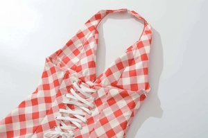 Detail view of red gingham dress showing lace-up front ties and halter neck design