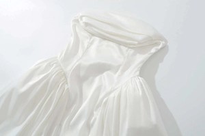 Détail d'une robe en satin blanc avec décolleté drapé élégant et manches plissées chic