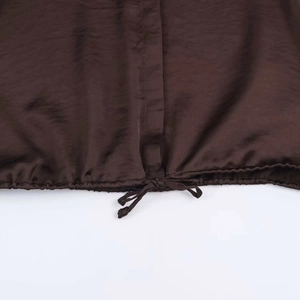 Detailed macro view of the drawstring hem on dark brown satin texture blouse