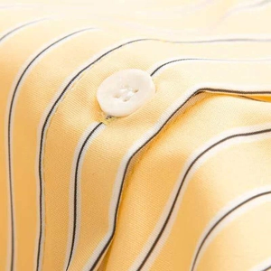 Detail of yellow and white striped fabric with a premium four-hole button and neat stitching