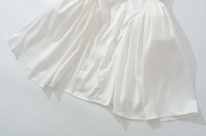Vue détaillée de l'ourlet plissé d'une robe en mousseline blanche avec coutures précises