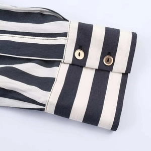 Close-up of double-button cuffs and metallic detail on a vertical striped shirt