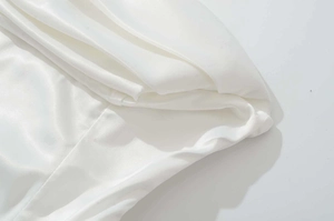 Vue détaillée montrant la texture élégante du satin blanc et le design drapé plissé