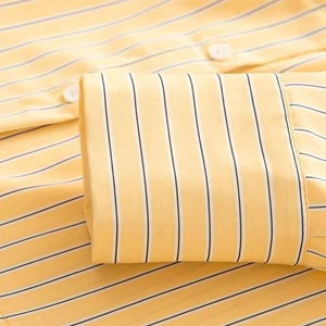 Detailed close-up of striped yellow shirt cuffs with white buttons and fine stitching