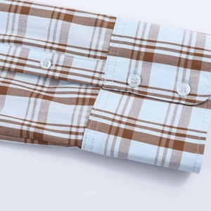 Detail view of plaid poplin shirt cuff featuring blue and brown checks and resin button