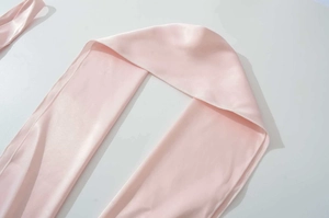 Dettaglio del tessuto satinato rosa chiaro con cuciture di qualità e consistenza seta
