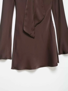 Détail d'une robe en satin marron foncé montrant la texture soyeuse et le col noué