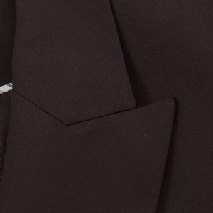 Détail du revers cranté et du tissu texturé sur un blazer sombre à double boutonnage