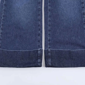 Detailed close-up showing the cuffed hem and high-quality dark blue denim fabric texture