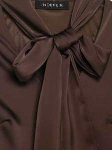 Détail d'une robe en satin marron foncé avec col à nœud élégant et texture de tissu soyeux