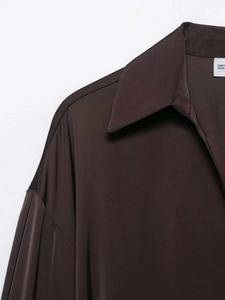 Détail du col et de l'épaule d'une chemise en satin marron à la texture soyeuse