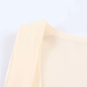 Detail of light beige tiered dress fabric with clean stitching and sheer chiffon texture