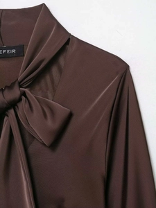 Détail du col à nœud papillon et étiquette de marque sur robe en satin de soie marron