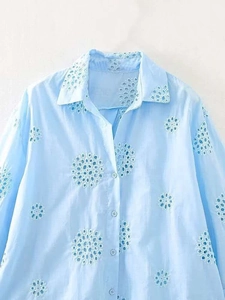 Close-up of light blue summer shirt featuring white eyelet embroidery and button details