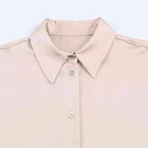 Close-up of lapel collar and silk-like satin fabric texture on a beige button-up shirt