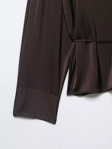 Détail d'une chemise en satin chocolat avec poignets larges et fine ceinture assortie
