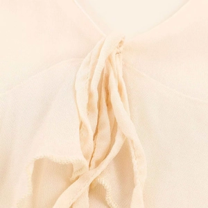 Detail view of the elegant V-neckline with pleated ties on a cream midi dress
