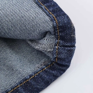 Detailed close-up of dark blue denim jeans with orange contrast double stitching on the hem