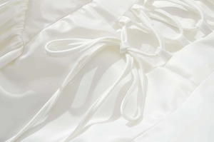 Détails d'une robe en satin blanc avec laçage croisé complexe et finitions en nœuds