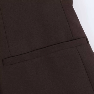 Vue détaillée de la texture du tissu marron foncé du blazer et de la poche passepoilée