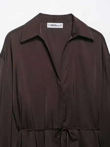 Détail du col d'une chemise en satin marron foncé avec étiquette de marque et ceinture
