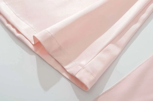 Dettaglio ravvicinato del tessuto rosa con rifinitura professionale dell'orlo a doppio ago