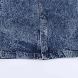 Detail of acid wash denim skirt hem featuring contrast orange stitching and split design