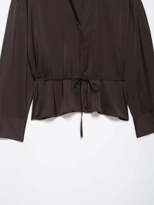 Détail de chemise en satin café noir à manches longues avec col en V et lien de taille