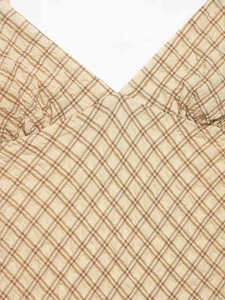 Détail du décolleté en V et tissu seersucker à carreaux orange d'une robe d'été