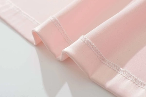 Dettaglio del tessuto dell'abito rosa con cuciture a doppio ago e trama del materiale