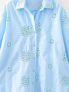 Detail view of light blue shirt featuring intricate white eyelet floral embroidery and buttons
