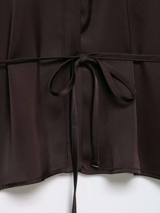 Détail d'une chemise en satin marron foncé avec ceinture nouée et texture de tissu sergé