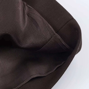 Vue macro de la texture à fines côtes et couture précise sur un tissu marron foncé