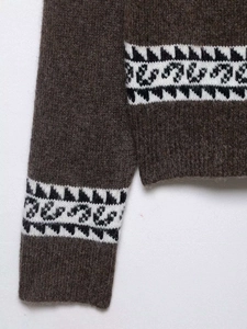 Texture détaillée du cardigan en laine marron avec motifs jacquard géométriques aux poignets