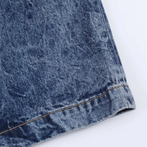 Detailed close-up of blue denim skirt hem featuring premium yellow stitching and wash texture