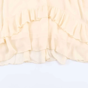 Close-up of layered ruffle details on a cream chiffon midi dress with delicate stitching