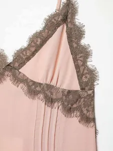 Detail of light pink V-neck top featuring delicate brown eyelash lace trim and silk texture