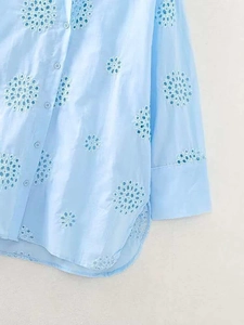 Detailed close-up of intricate light blue floral Sangallo embroidery on cotton shirt