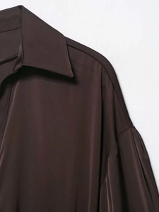 Détail du col en satin et de l'épaule tombante sur une blouse élégante marron foncé