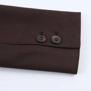 Gros plan des boutons de manchette sur un blazer marron foncé à texture sergé fine