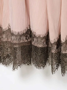 Detail of light pink pleated chiffon fabric with brown eyelash lace trim on the dress hem