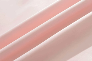 Dettaglio del tessuto rosa tenue dell'abito estivo con texture liscia e drappeggio