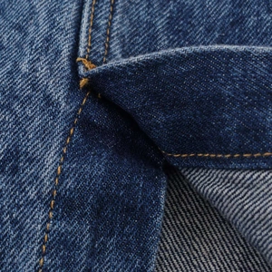 Close-up of high-waisted denim skirt with dark blue twill fabric and brown stitching