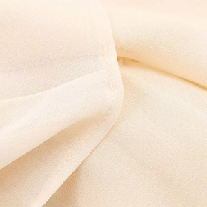 Close-up of light beige pleated fabric with detailed hem stitching on midi dress