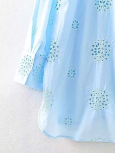 Detail of light blue shirt sleeve with intricate white eyelet embroidery and lace texture