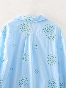 Close-up of light blue summer shirt featuring white eyelet embroidery and floral cut-outs