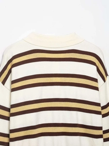 Close-up of crew neck knitwear with cream, dark brown, and ginger yellow stripes