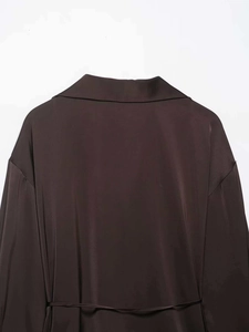 Détail du col d'une chemise en satin marron foncé et des finitions de couture d'épaule